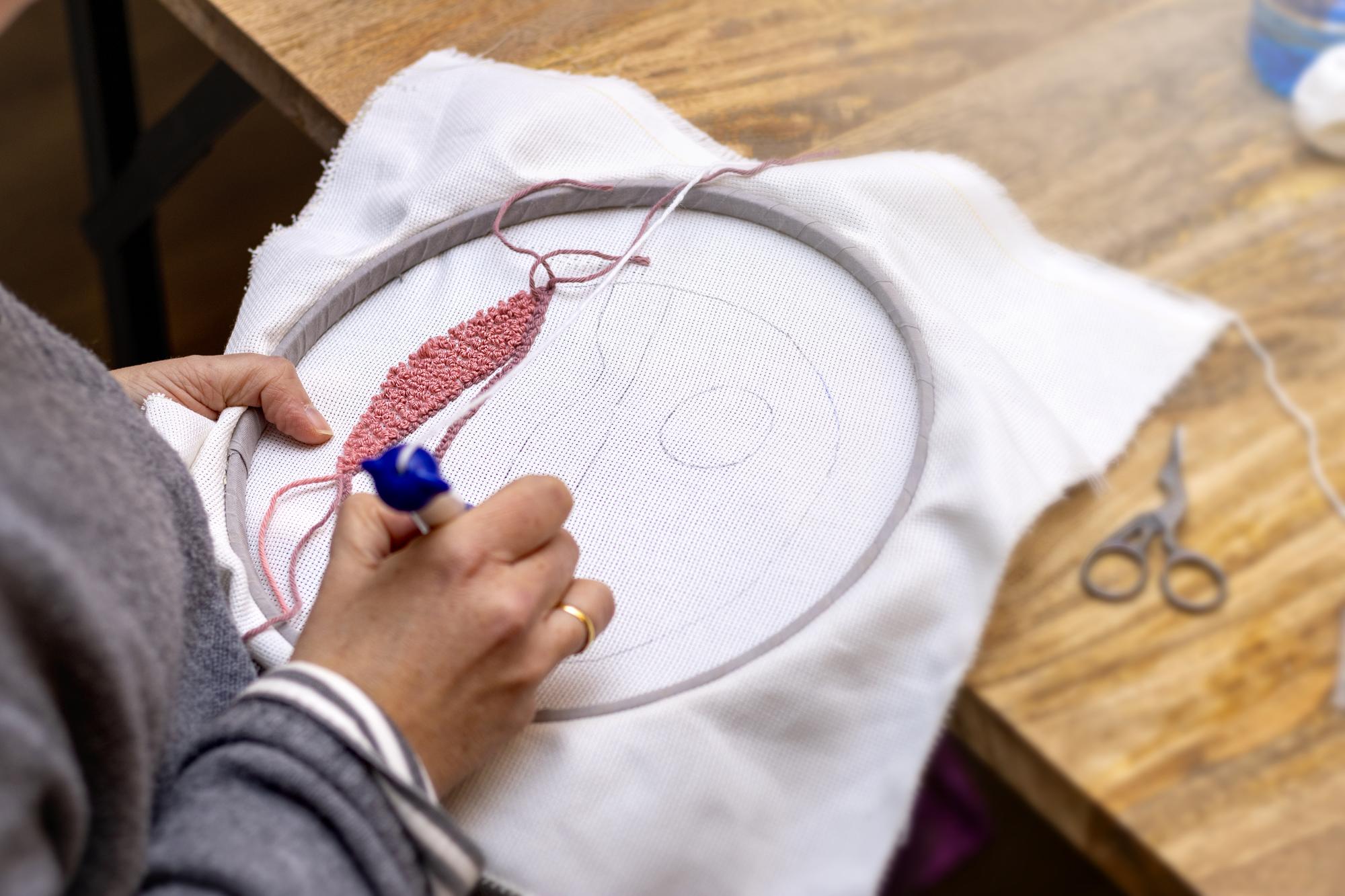 atelier hands pinning fabric to hoop